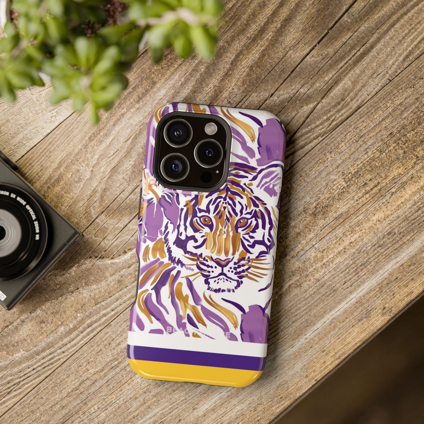 Baton Rouge MagSafe Tough Case for iPhone with purple and yellow tiger design on a wooden surface