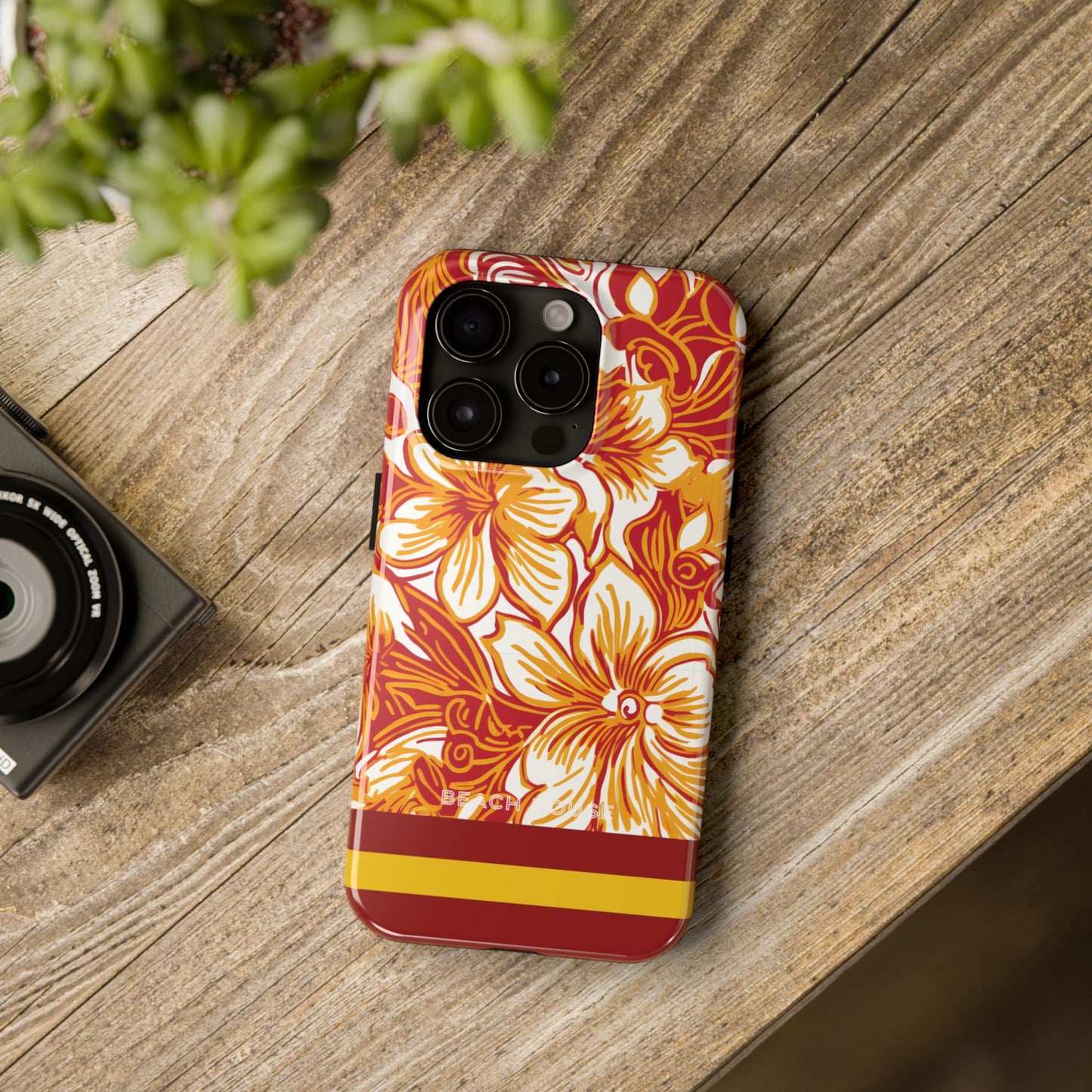 Floral patterned Los Angeles Tough Case for iPhone on a wooden surface with a camera and plant in the background