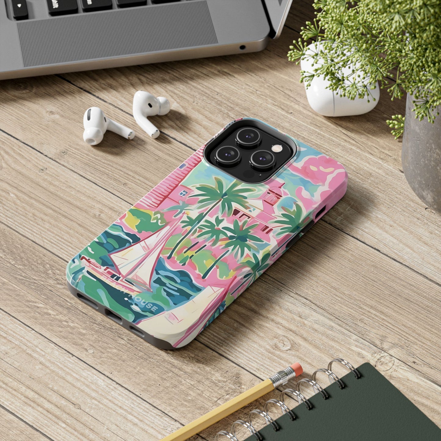 St. Simon Phone case with tropical design on a wooden surface with laptop, earbuds, and notebook.