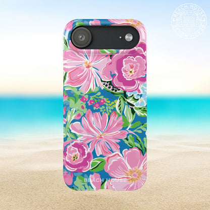 Madeira Slim Case for iPhone 17 Air with pink flowers on a blue background, set against a beach scene.