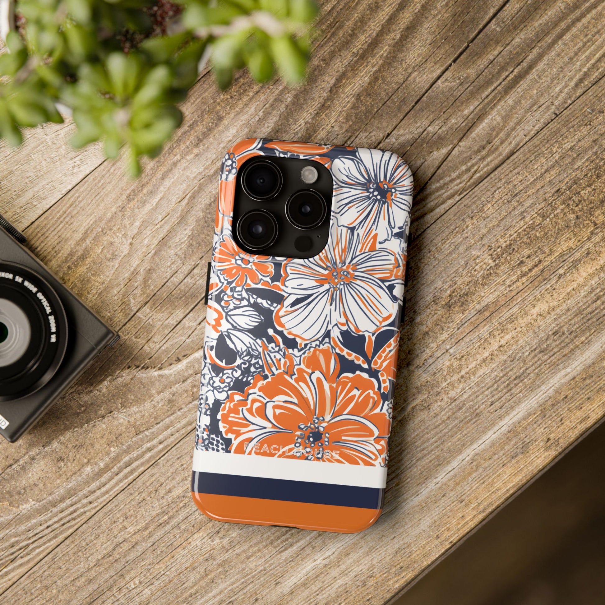 Charlottesville Tough Case for iPhone on a wooden surface with a camera and plant in the background