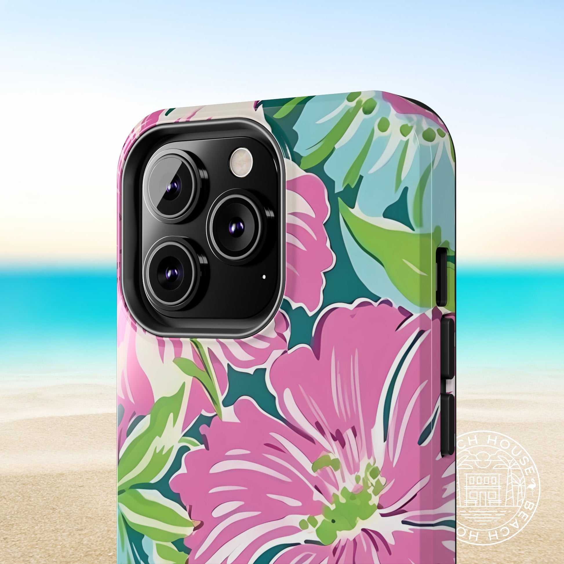 Close up view of the Seaside Tough Case for iPhone with pink flowers and green leaves on a beach background
