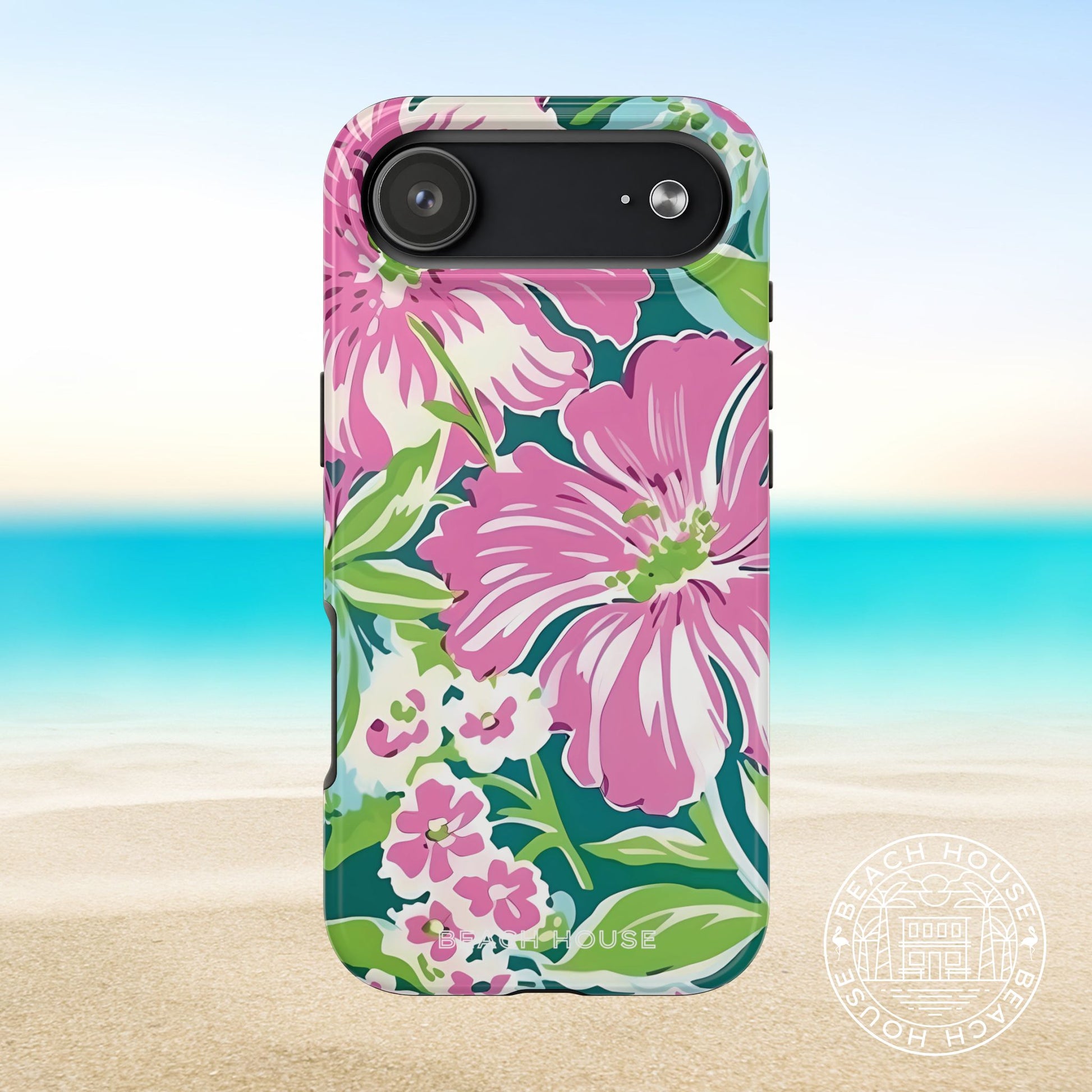 Seaside Tough Case for iPhone 17 Air with pink flowers on a blue and green background, placed on sand with ocean view.