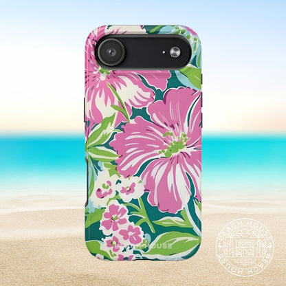 Seaside Tough Case for iPhone 17 Air with pink flowers on a blue and green background, placed on sand with ocean view.