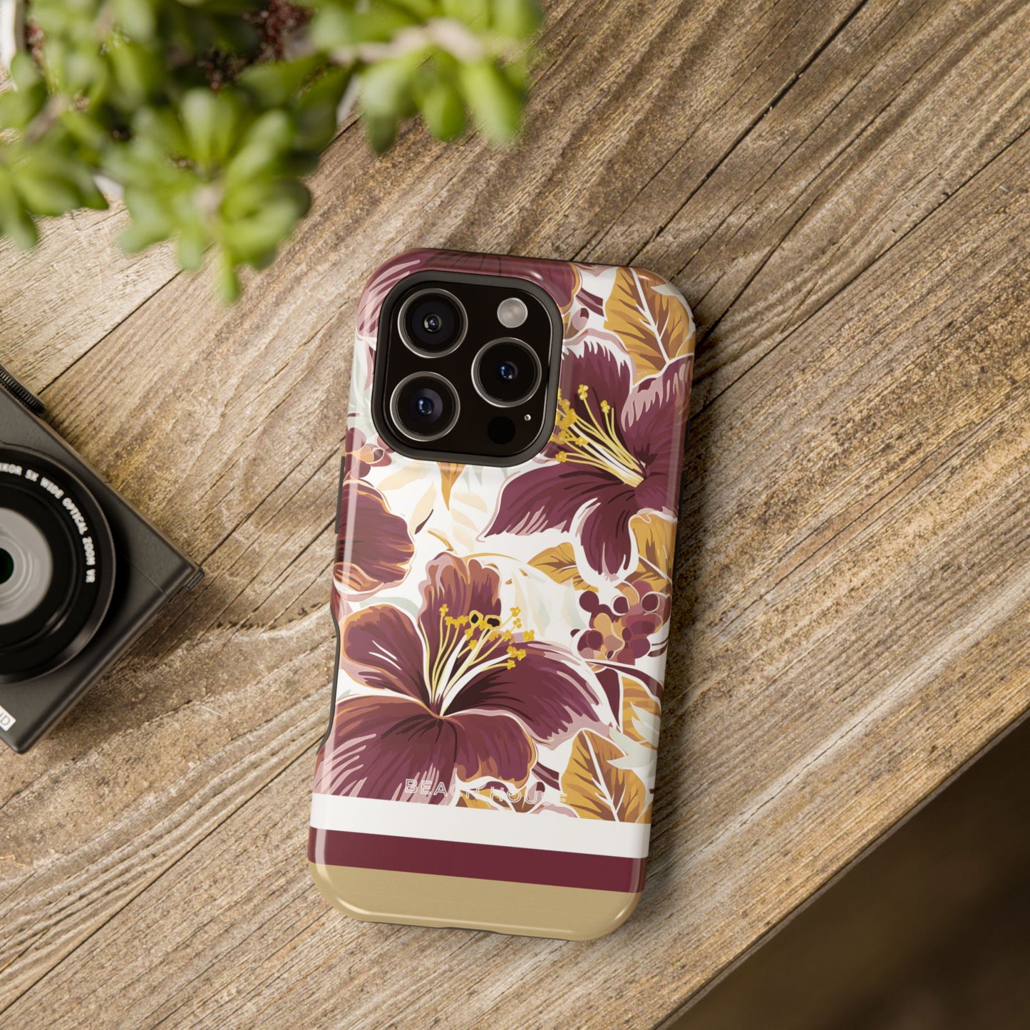 Tallahassee MagSafe Tough Case for iPhone on a wooden surface with a camera and plant in the background