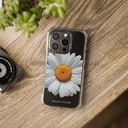 Phone case with a daisy design on a wooden surface next to a camera and plant.