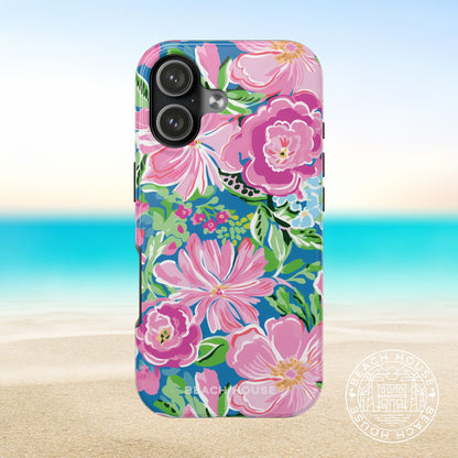 Madeira Tough Case for iPhone 17 with pink and green flowers on a blue background, placed on sand with ocean view.