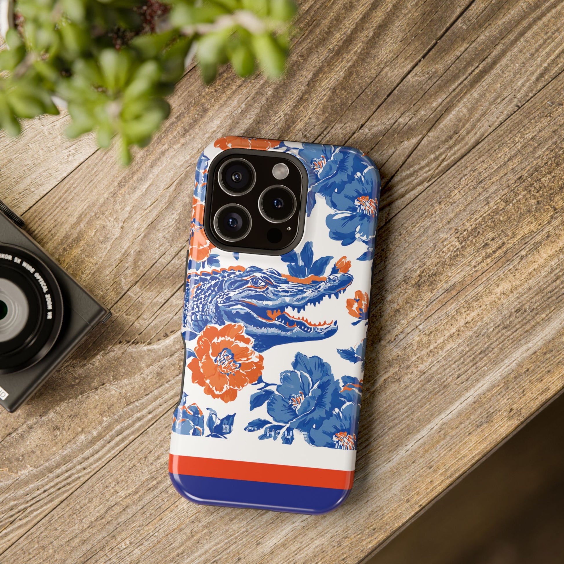 Phone case with floral and crocodile design on a wooden surface