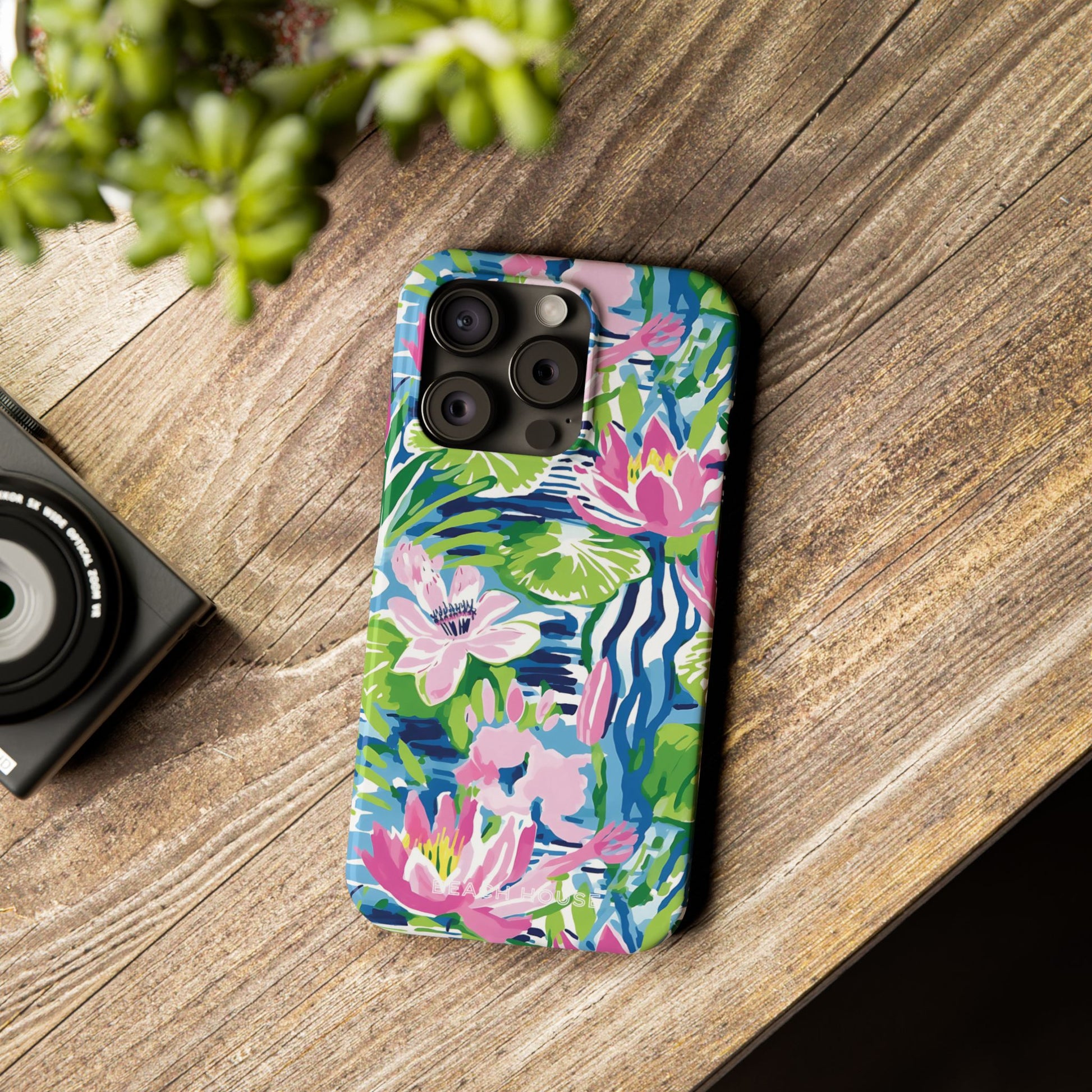 Cute Everglades Slim Case for iPhone on a wooden surface with a camera and plant in the background