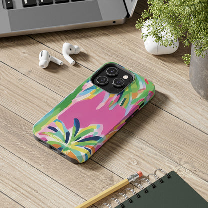 Colorful Boca Tough case for iPhone on a wooden desk with laptop, earbuds, and notebook.