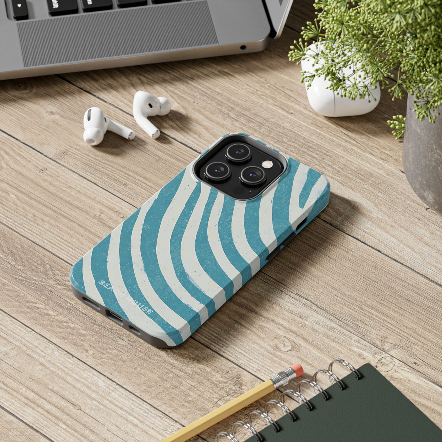 Holmes Beach Tough Case for iPhone with blue and white striped pattern on a wooden surface with laptop, earbuds, and notebook.