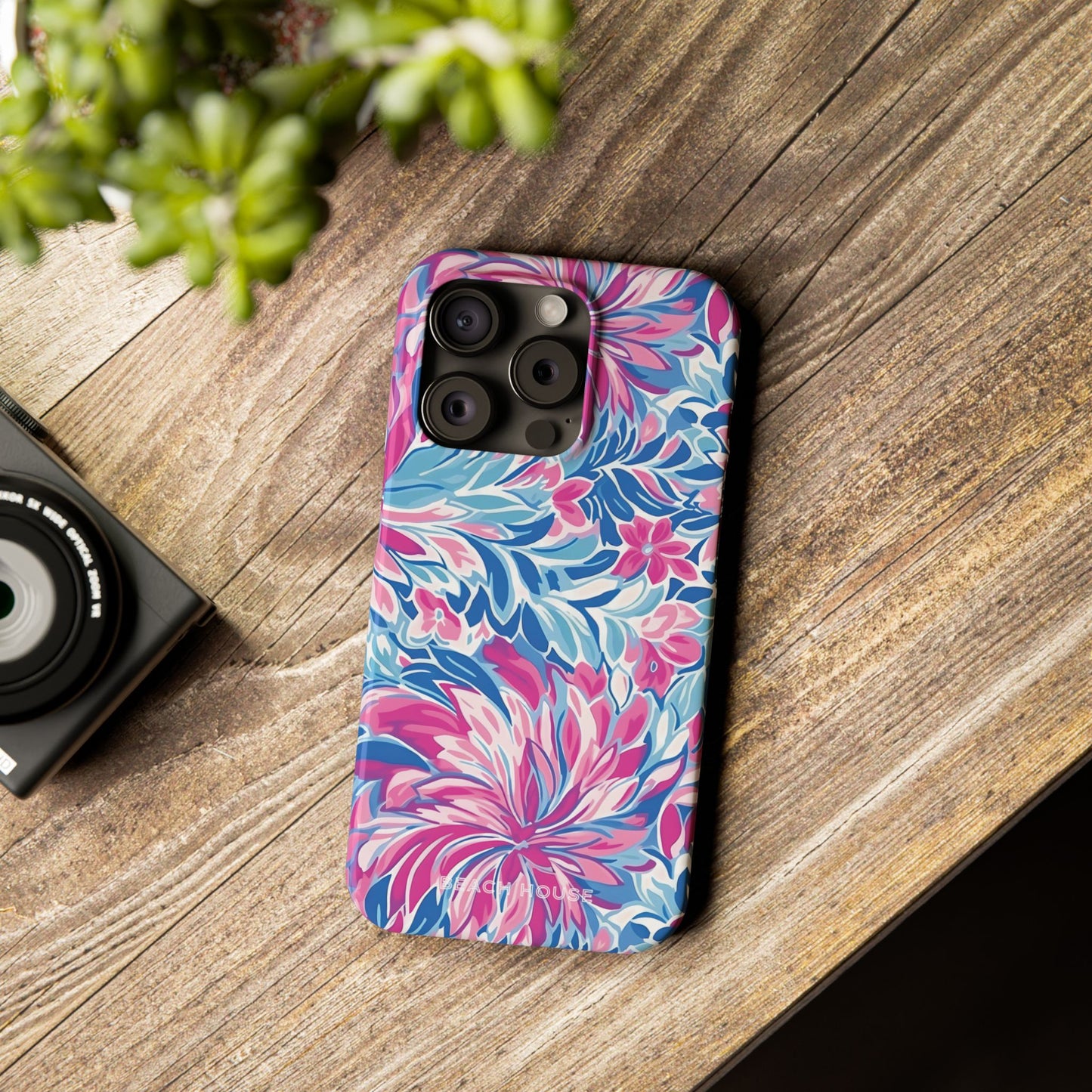 Destin Slim Case for iPhone with floral pattern on a wooden surface next to a camera and plant