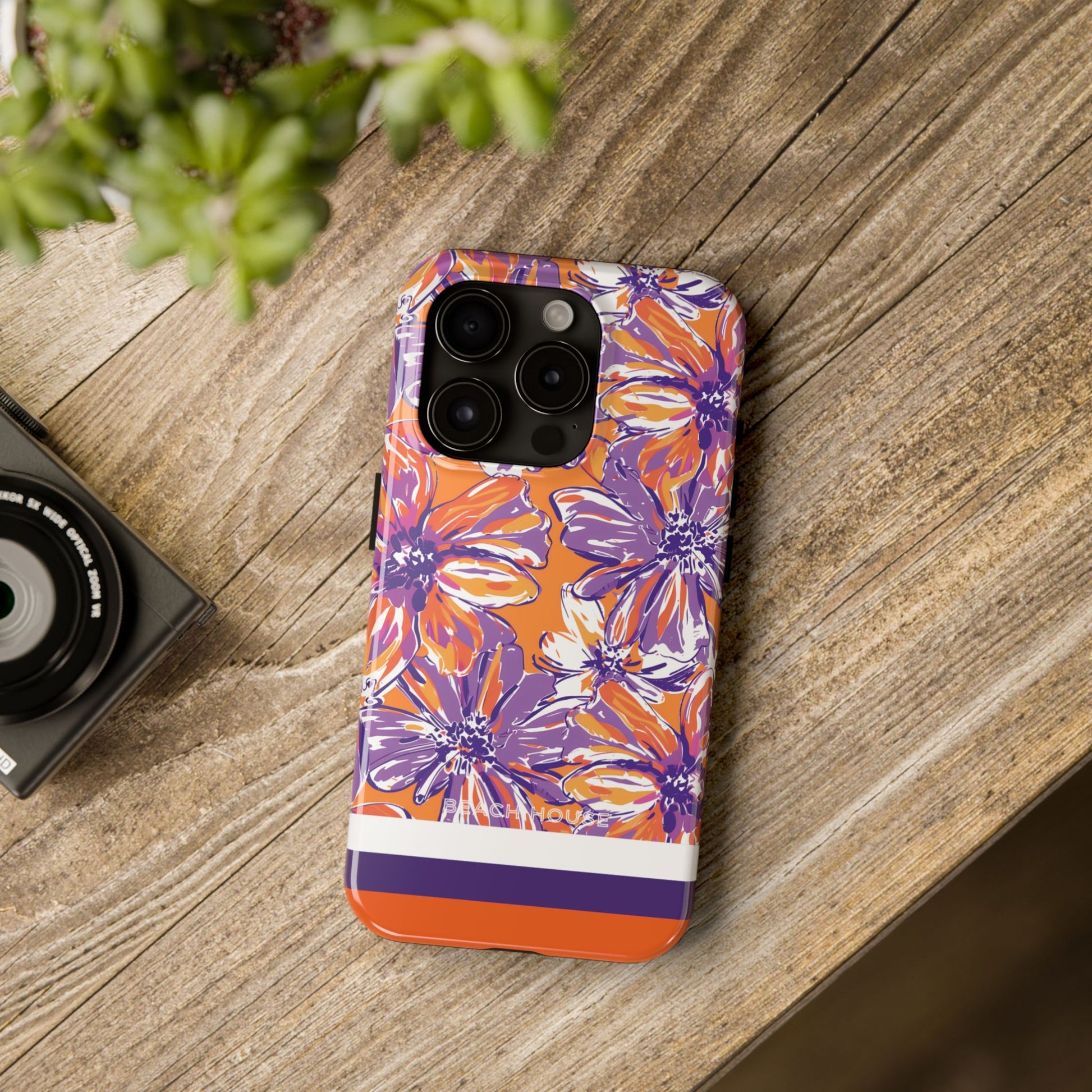 Clemson Tough Case for iPhone with floral design on a wooden surface next to a camera and plant