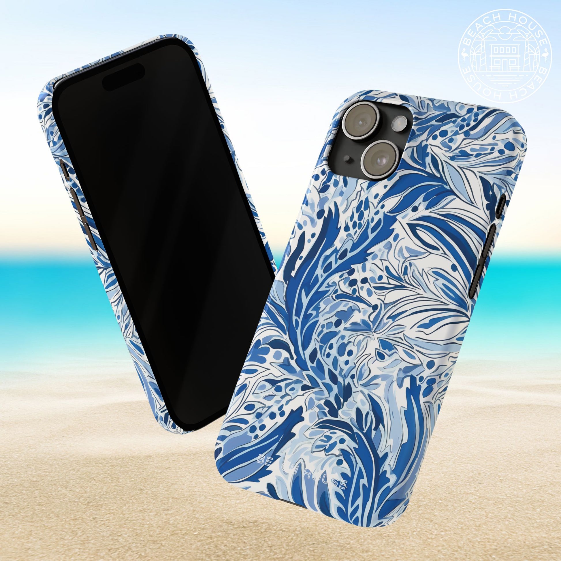 Front and back view of a blue and white floralNags Head Slim Case for iPhone on a beach background