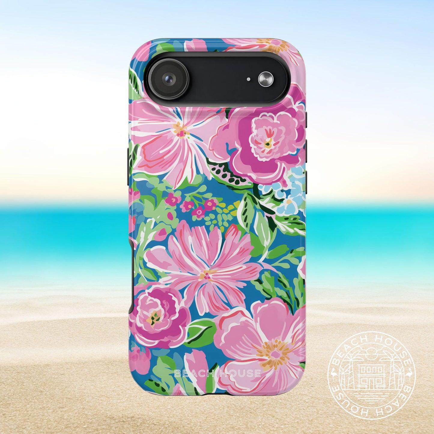 Madeira Tough Case for iPhone 17 Air with pink flowers on a blue background, placed on sand with ocean view.