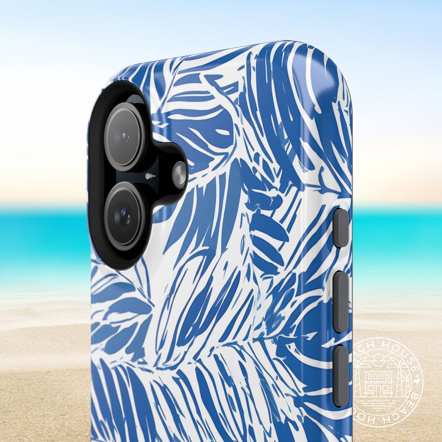 Close up shot of the tropical artwork and buttons on the Hampton MagSafe Tough Case for iPhone with a blurred beach background