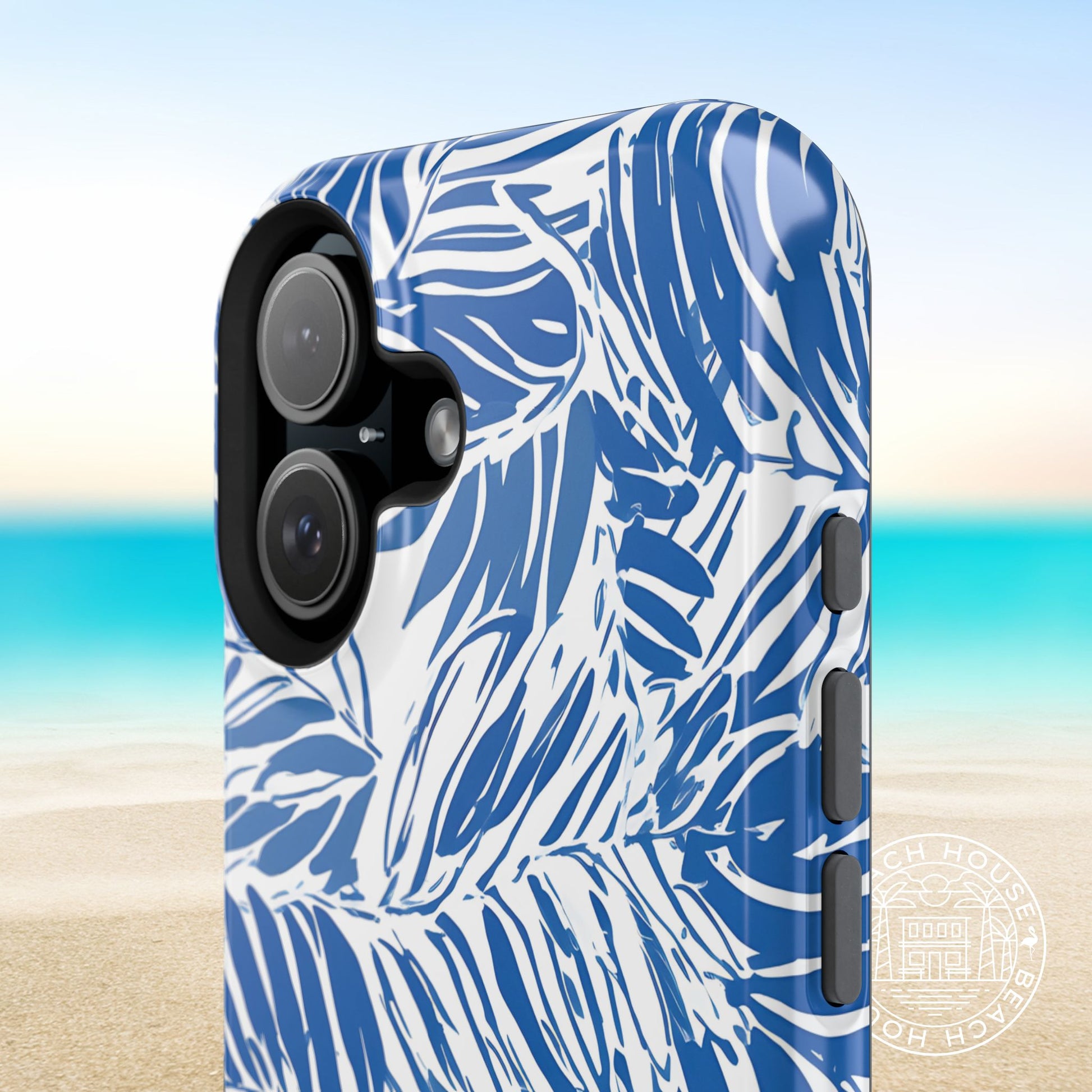 Close up shot of the tropical artwork and buttons on the Hampton MagSafe Tough Case for iPhone with a blurred beach background