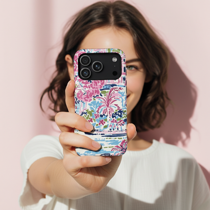 Woman holding a phone with a colorful floral Amelia case against a pink background
