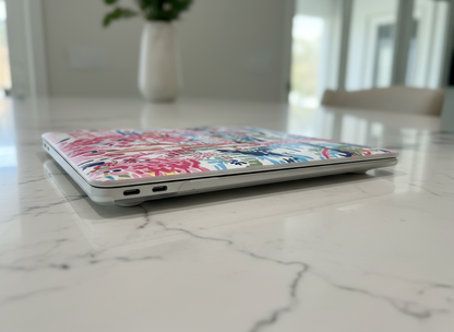 Laptop with a colorful floral Amelia MacBook Case on a marble surface