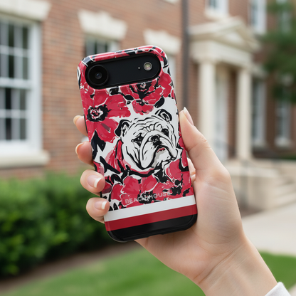 Athens Tough case for iPhone with bulldog and floral design held by a person outdoors.