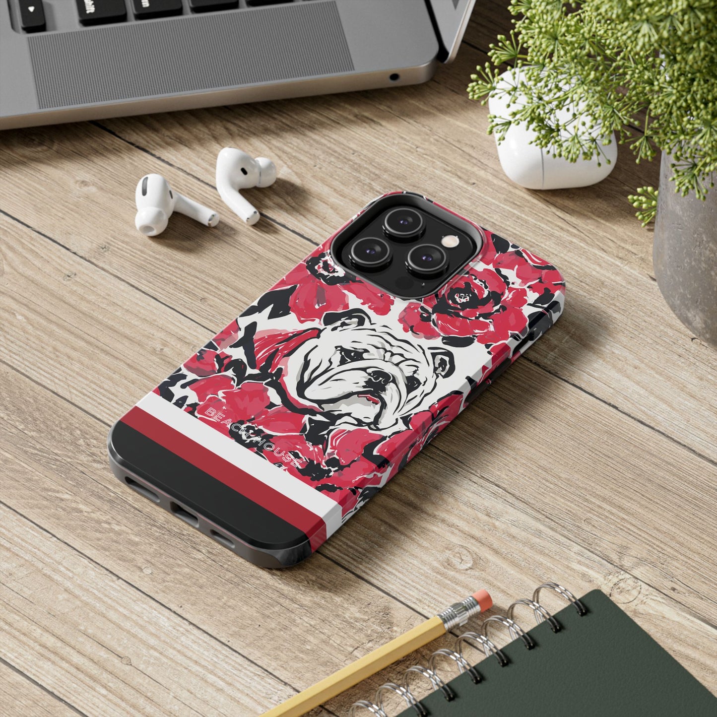 Athens Tough Case for iPhone with bulldog design on a wooden surface with laptop, earbuds, and notebook.
