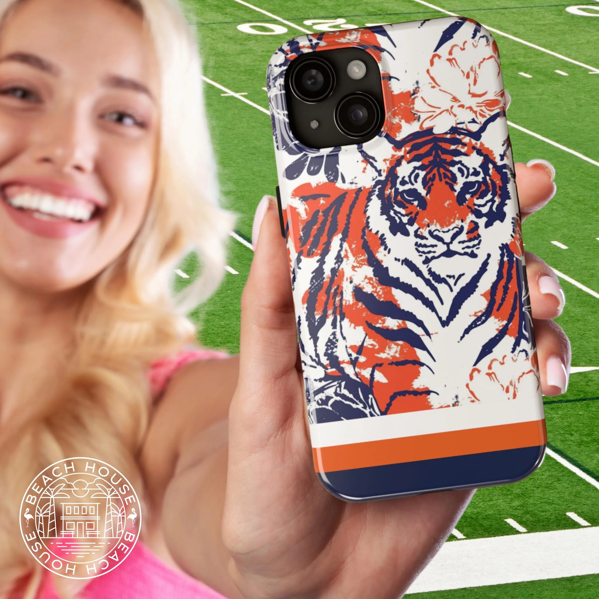 Person holding a Auburn Tough Case for iPhone with tiger design on a football field background