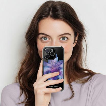 Woman holding a phone with a colorful case against a plain background