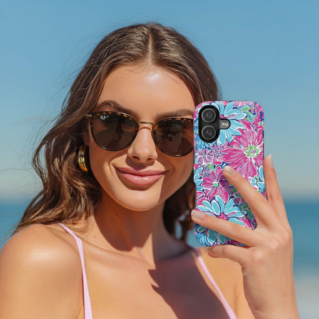 Woman holding a phone with a colorful floral case on a beach