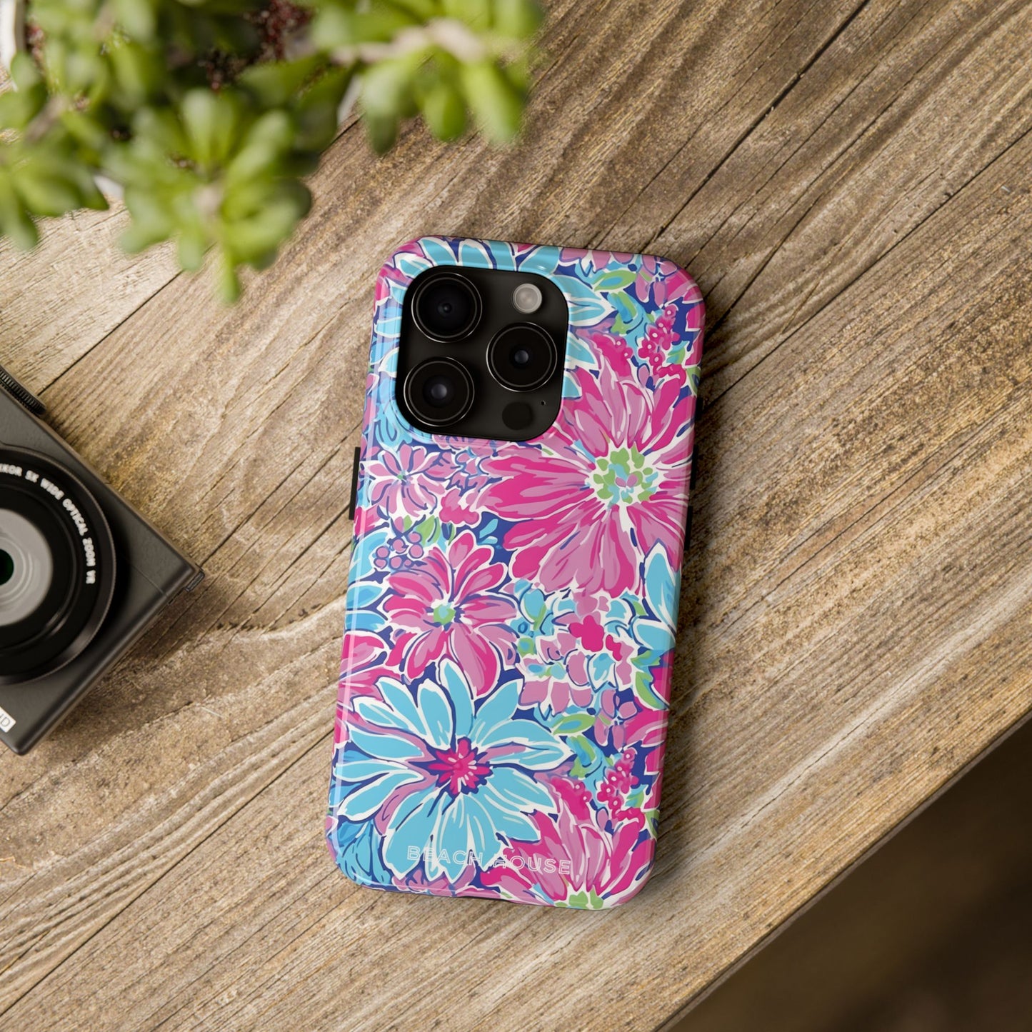 Floral Bimini Tough Case for iPhone on a wooden surface with a camera and plant in the background