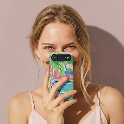 Woman holding a phone with a colorful Delray MagSafe Tough case against a beige background