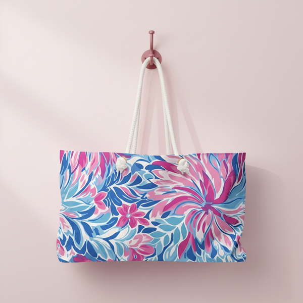 Destin weekender tote bag with pink and blue floral pattern hanging on a pink wall.