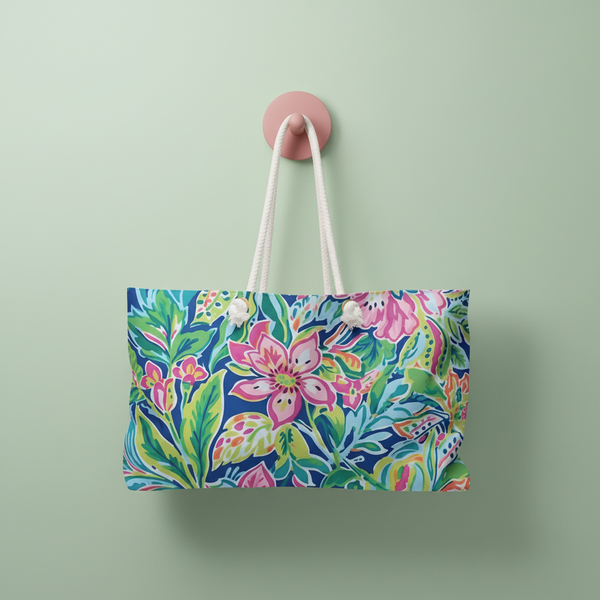 Tropical themed Fernandina Weekender tote bag with white rope handles, hanging on a pink hook against a green wall