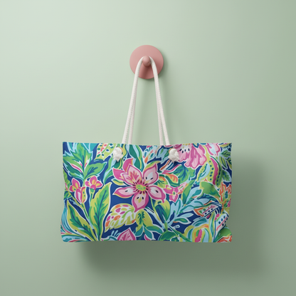 Tropical themed Fernandina Weekender tote bag with white rope handles, hanging on a pink hook against a green wall