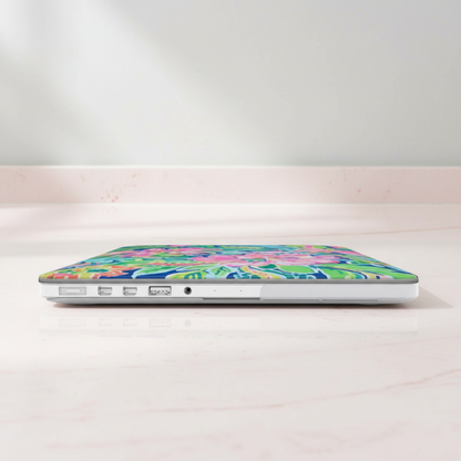 Laptop with a colorful floral Fernandina MacBook Case on a white surface