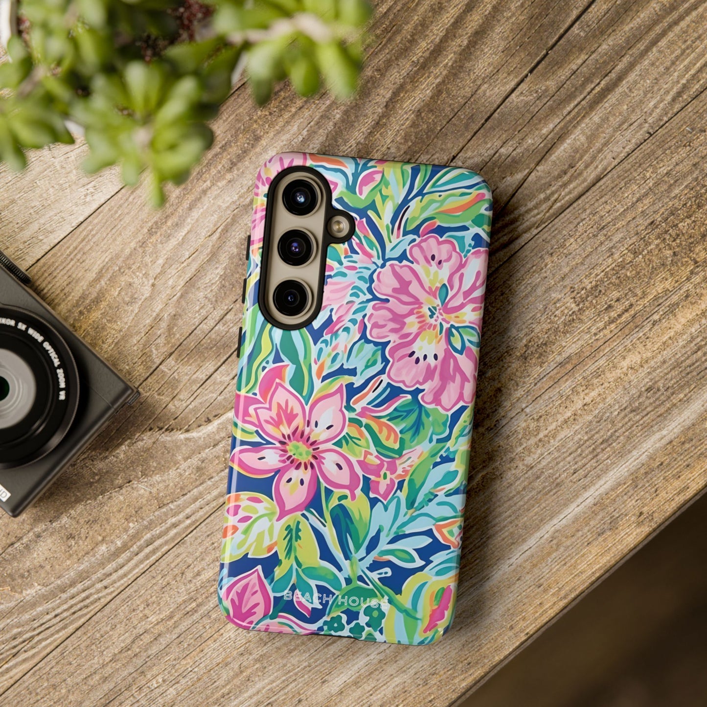 Colorful floral Fernandina Tough Case for Galaxy on a wooden surface with a camera and plant in the background