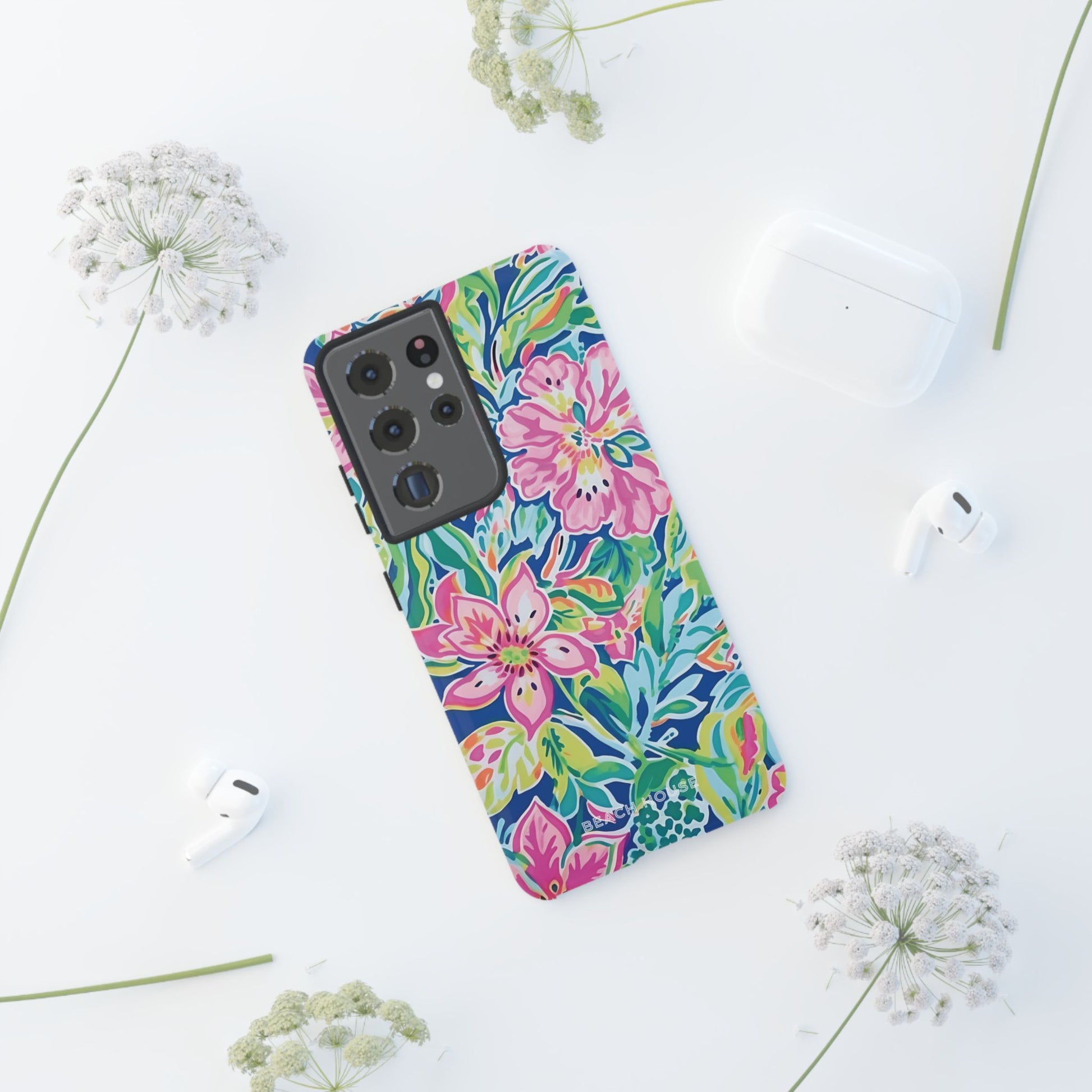 Fernandina Tough Case for Galaxy with colorful floral design on a white surface with earbuds and flowers nearby