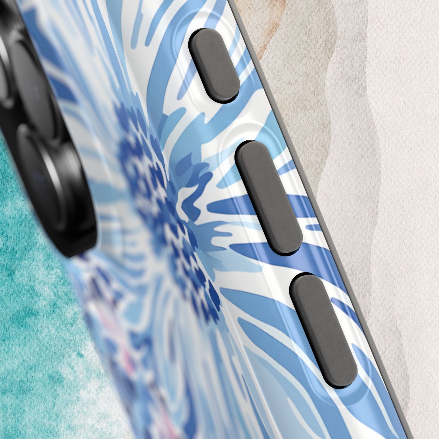 Huntington MagSafe Tough Phone case with blue floral design and black accents on a beach background