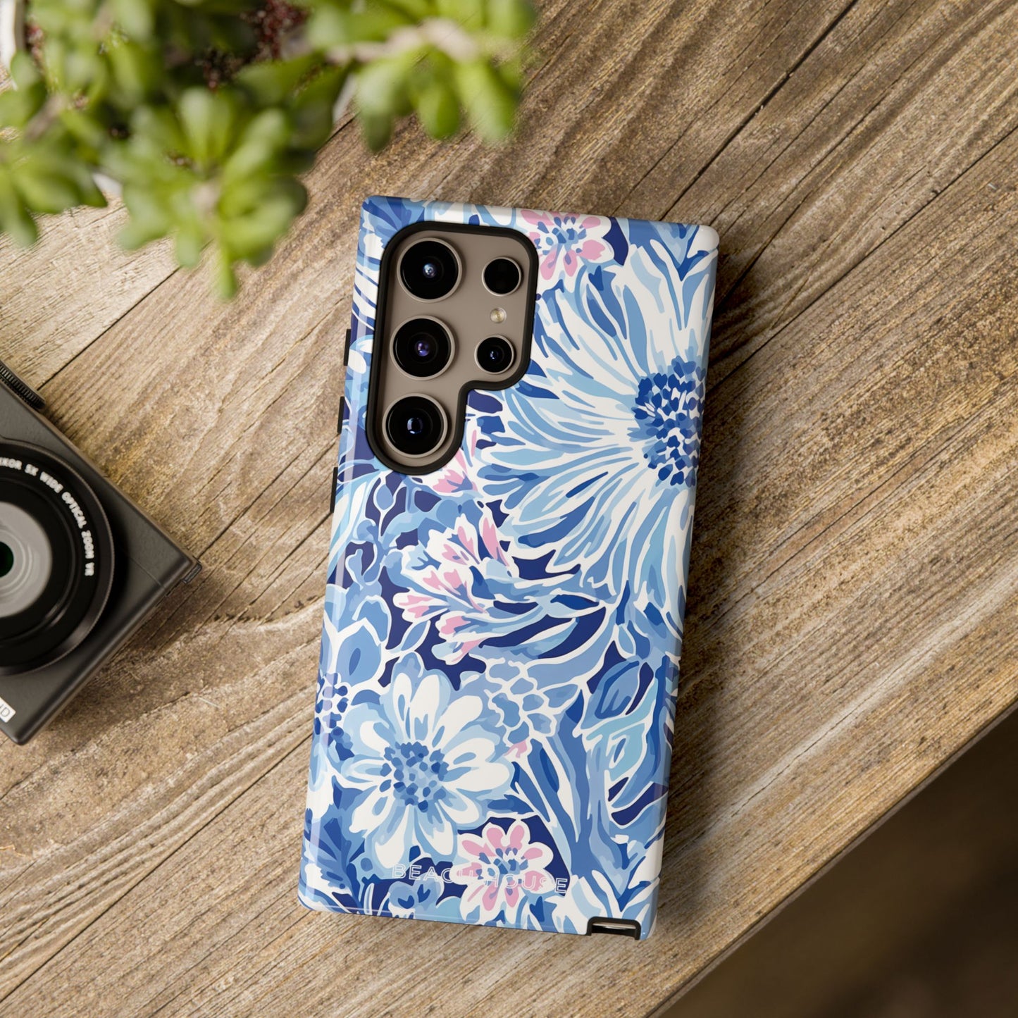 Floral Huntington Tough Case for Galaxy on a wooden surface with a camera and plant in the background