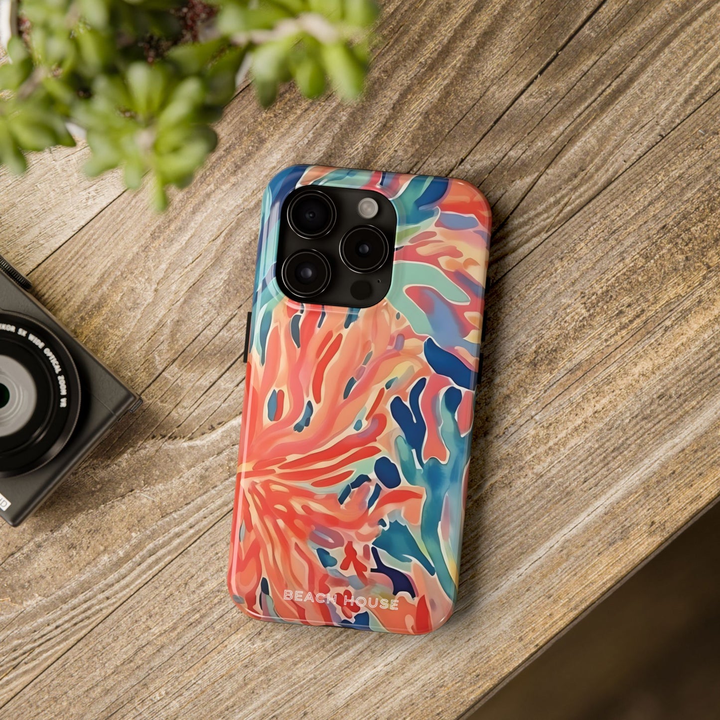 Key Biscayne Tough Case for iPhone with a tropical coral pattern on a wooden surface next to a camera.
