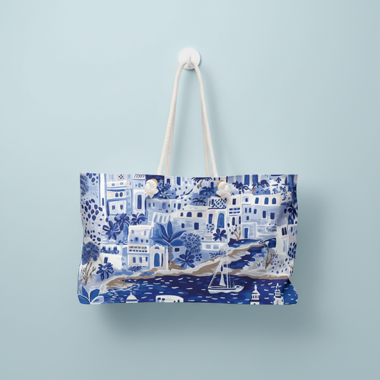 Santorini Weekender tote bag with blue and white coastal pattern hanging on a light blue wall