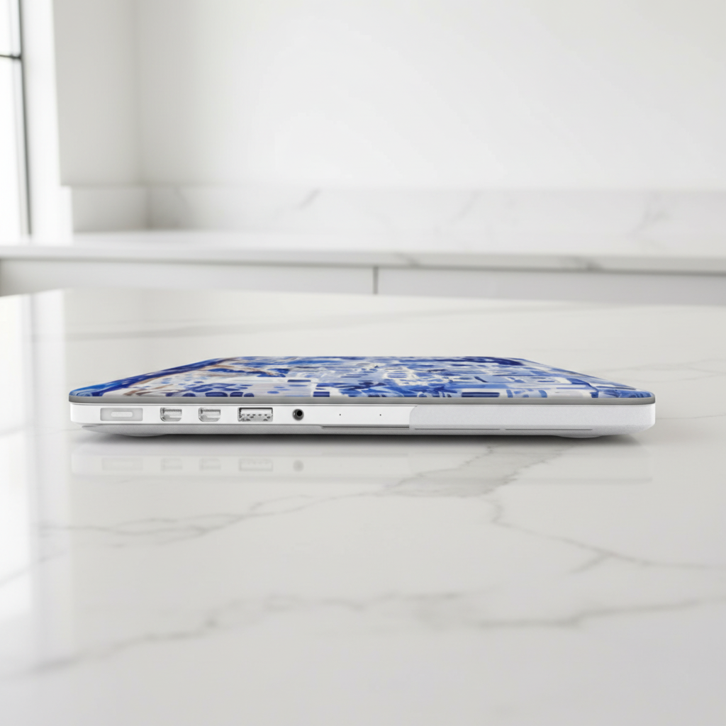 Laptop with a blue and white Santorini MacBook Case on a white marble surface