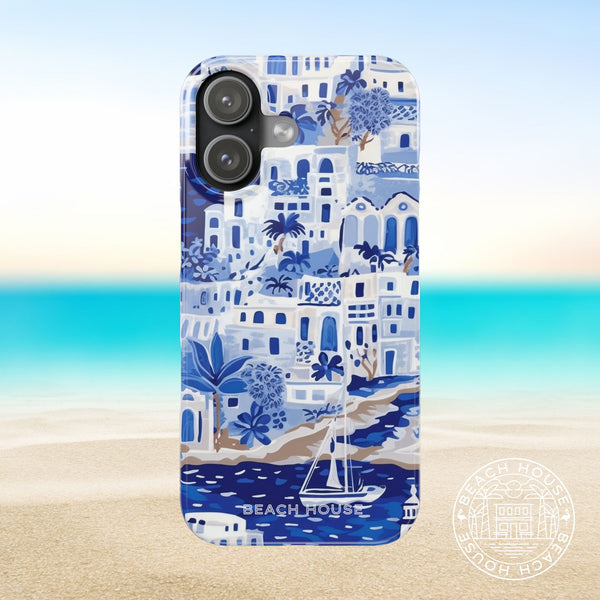 Santorini Slim Case for iPhone 17 with coastal design featuring buildings, sailboats, and palm trees on a beach background.