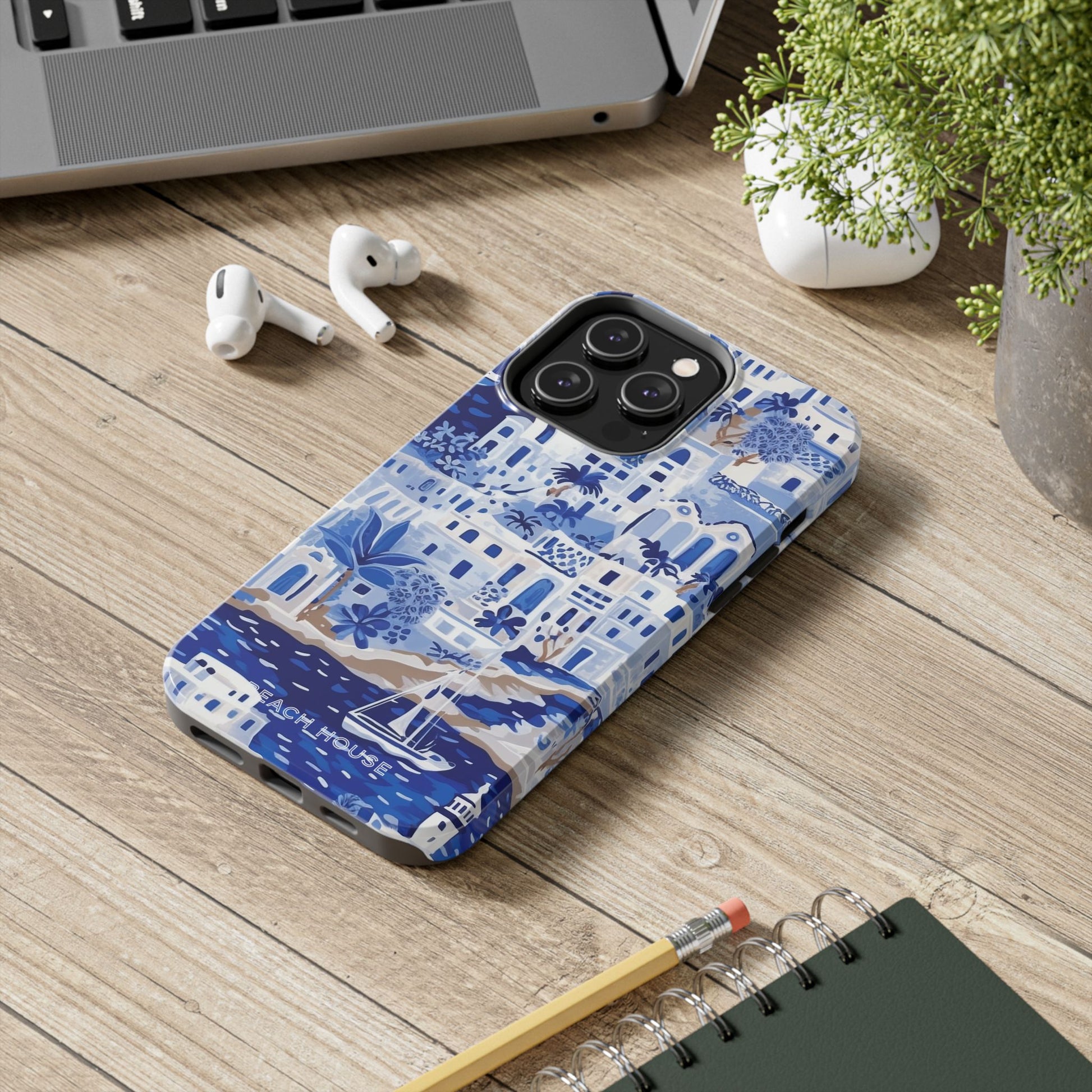 Santorini Tough Case for iPhone with blue and white pattern on a wooden surface with laptop, earbuds, and notebook.