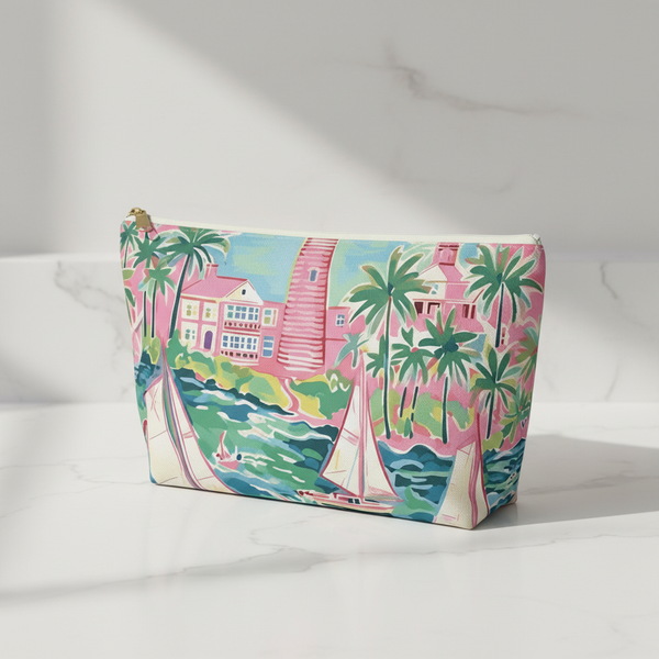 Cosmetic bag with tropical design featuring a pink house, palm trees, and sailboats on a white background.