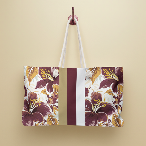 Floral Tallahassee Weekender Tote Bag with a striped design hanging on a hook against a gold background